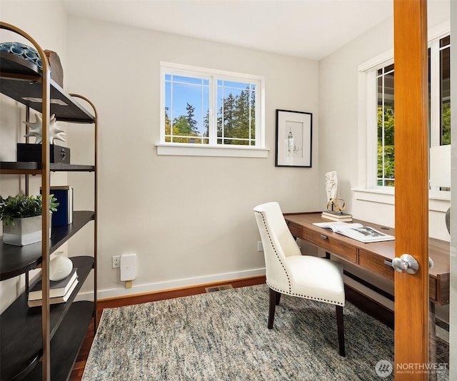 office with visible vents, baseboards, wood finished floors, and a healthy amount of sunlight