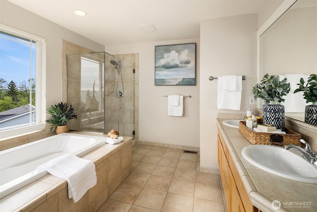 bathroom featuring tile patterned floors, a sink, a bath, and a stall shower