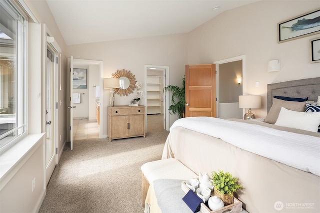 bedroom with multiple windows, light carpet, vaulted ceiling, and a spacious closet