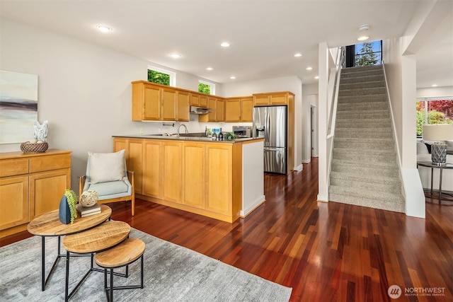 kitchen featuring dark wood-style flooring, a peninsula, stainless steel fridge, under cabinet range hood, and recessed lighting