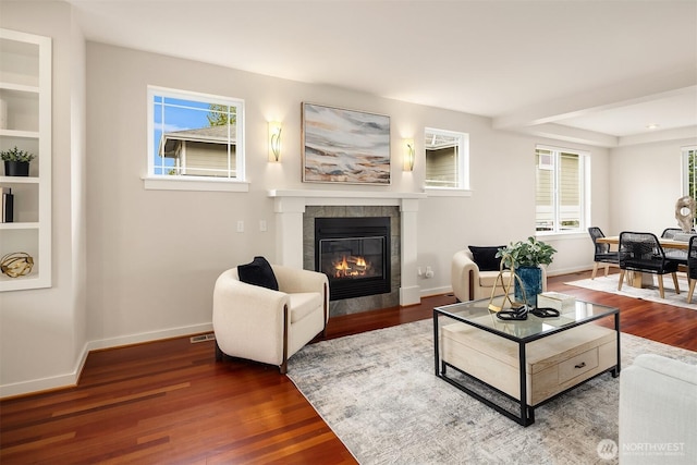 living area featuring baseboards, wood finished floors, and a fireplace