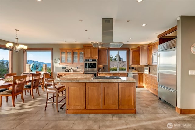 kitchen with island range hood, built in appliances, a healthy amount of sunlight, and light countertops