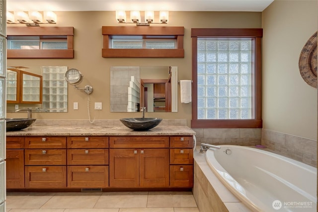 bathroom featuring a healthy amount of sunlight, a garden tub, and a sink