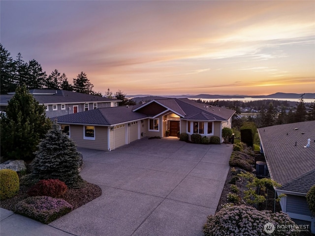 view of front of house with driveway, metal roof, central AC, and a garage