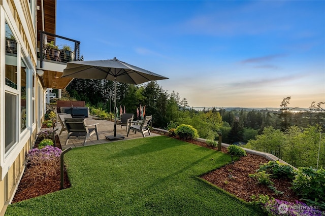 yard at dusk with a balcony, a patio, and an outdoor hangout area