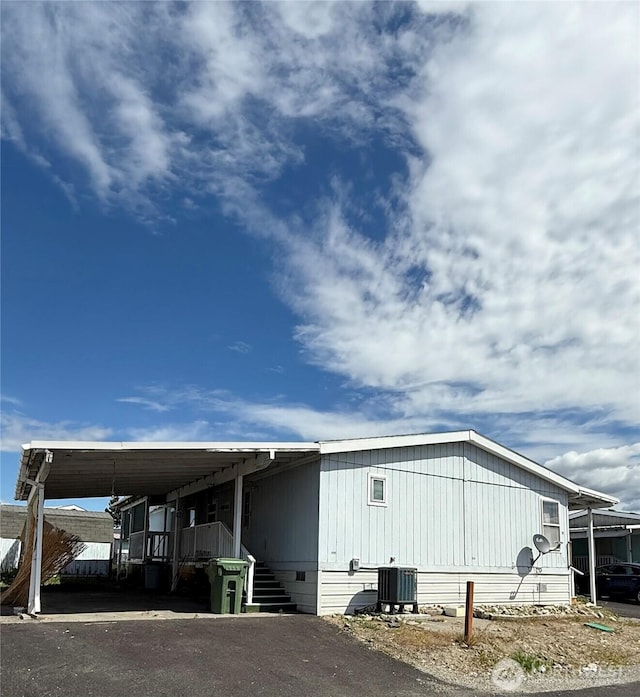 exterior space featuring central air condition unit, stairway, driveway, and a carport