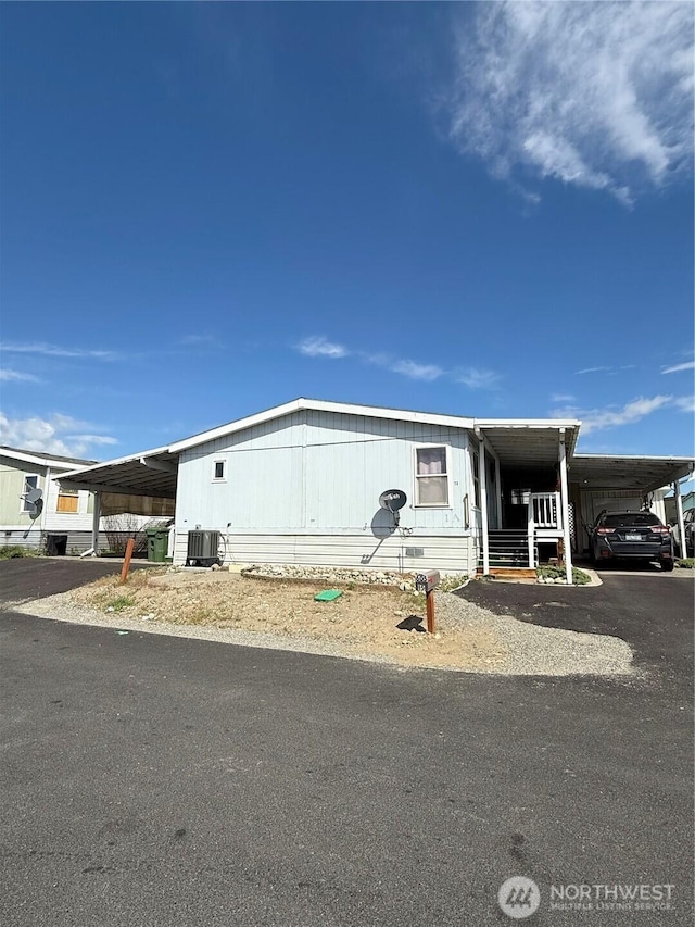manufactured / mobile home with central air condition unit, a carport, and aphalt driveway