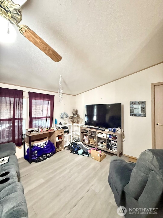 living room with a textured ceiling, ceiling fan, wood finished floors, and vaulted ceiling