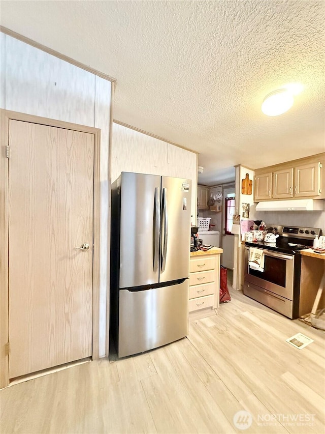 kitchen with light brown cabinetry, appliances with stainless steel finishes, light wood finished floors, a textured ceiling, and under cabinet range hood