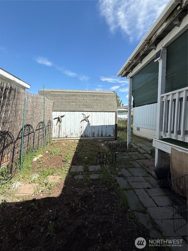 view of yard featuring an outdoor structure, a shed, and fence