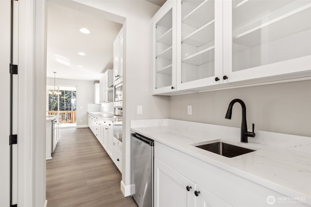 kitchen featuring light stone countertops, a sink, white cabinetry, and light wood-style floors