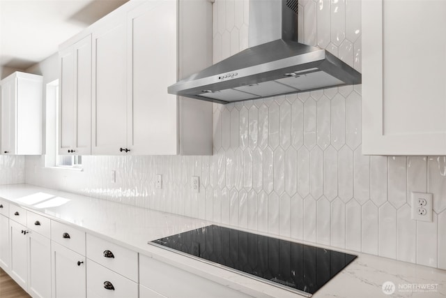 kitchen with wall chimney exhaust hood, white cabinets, black electric stovetop, and decorative backsplash