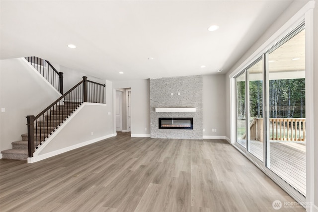 unfurnished living room featuring baseboards, light wood-style flooring, recessed lighting, and stairs
