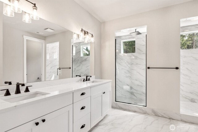 bathroom with a marble finish shower, marble finish floor, double vanity, and a sink