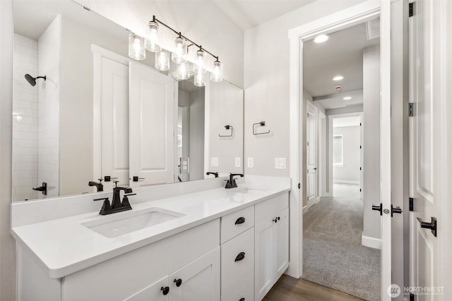 full bath with recessed lighting, walk in shower, double vanity, and a sink