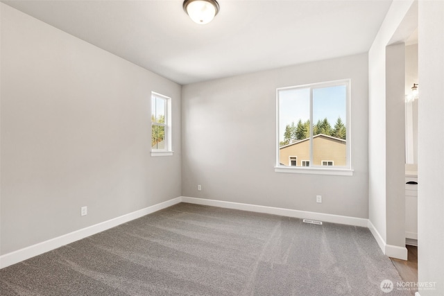 carpeted empty room featuring baseboards and visible vents