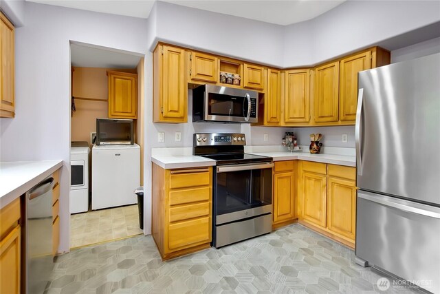 kitchen with independent washer and dryer, stainless steel appliances, light floors, and light countertops