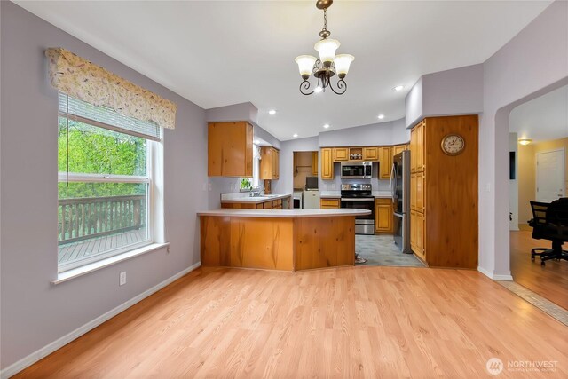 kitchen featuring brown cabinets, a peninsula, a notable chandelier, light wood-style floors, and stainless steel appliances