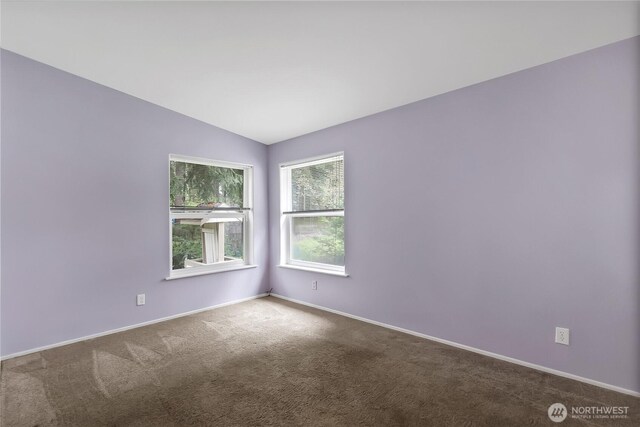 carpeted empty room with baseboards and vaulted ceiling