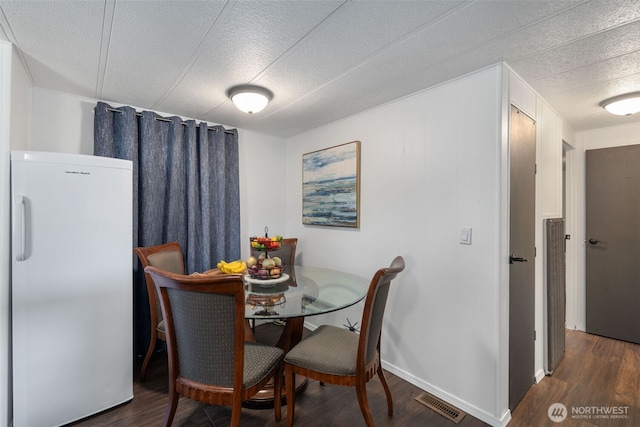 dining room featuring baseboards, a textured ceiling, visible vents, and wood finished floors