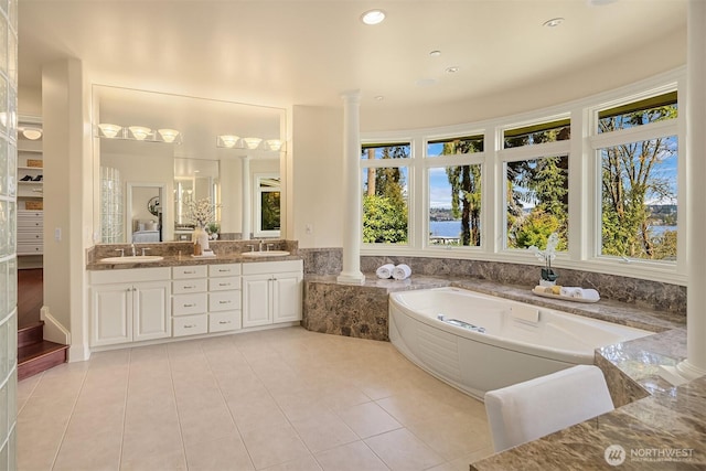 bathroom with a garden tub, a sink, tile patterned floors, and ornate columns