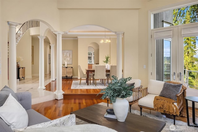 interior space with crown molding, french doors, arched walkways, wood finished floors, and a high ceiling