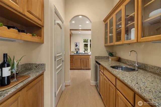 bar with recessed lighting, arched walkways, stainless steel dishwasher, light wood-style flooring, and a sink