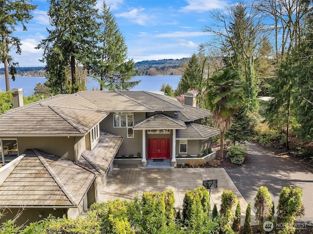 view of front of house featuring a water view, a tiled roof, and a chimney