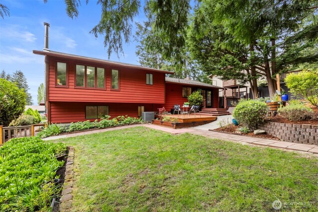 view of front of house with cooling unit, a wooden deck, and a front yard