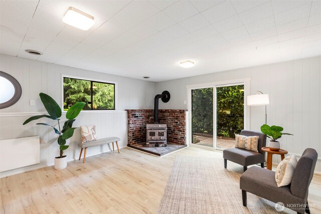 living room featuring a wood stove, wood finished floors, and a wealth of natural light