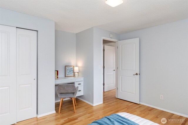 bedroom with baseboards, a closet, light wood finished floors, and a textured ceiling