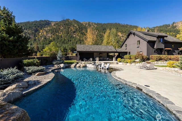 8105 Icicle Rd, Leavenworth, WA 98826 - view of swimming pool featuring a forest view, a fenced in pool, a mountain view, fence, and a patio area