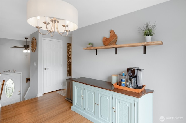 foyer entrance with ceiling fan with notable chandelier and light wood finished floors