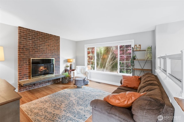 living area with baseboards, visible vents, wood finished floors, and a fireplace