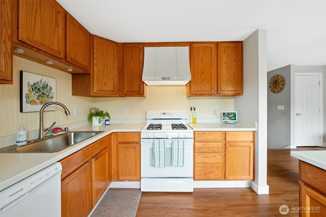 kitchen featuring a sink, light countertops, light wood finished floors, white appliances, and extractor fan