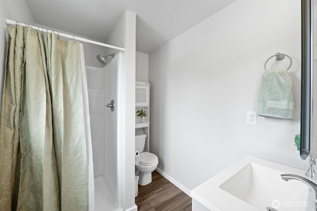 full bath featuring toilet, a sink, curtained shower, and wood finished floors