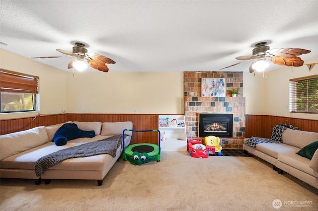carpeted living room featuring wooden walls, a ceiling fan, a textured ceiling, and wainscoting
