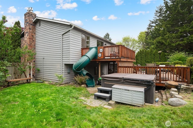 back of property with fence, a hot tub, a wooden deck, a chimney, and a yard