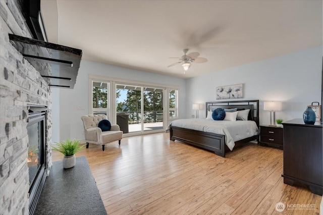 1447 Everette Ln, Freeland, WA 98249 - bedroom with a stone fireplace, light wood-style floors, ceiling fan, and access to exterior