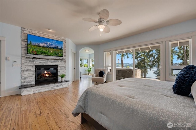 1447 Everette Ln, Freeland, WA 98249 - bedroom featuring a fireplace, ceiling fan, access to outside, hardwood / wood-style flooring, and arched walkways