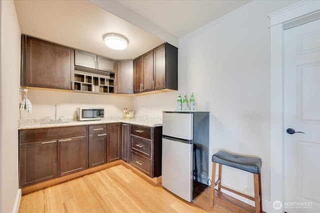 1447 Everette Ln, Freeland, WA 98249 - kitchen with dark brown cabinets, light stone counters, appliances with stainless steel finishes, a sink, and light wood-style floors