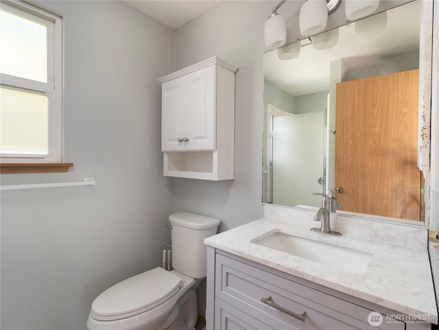 full bathroom featuring a shower with shower door, vanity, and toilet