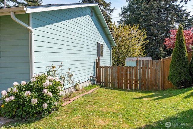view of side of home with fence and a lawn