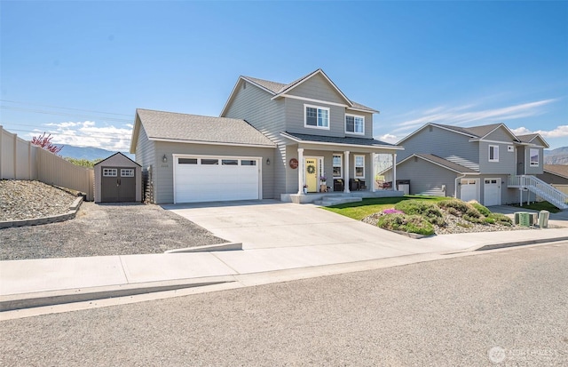 view of front of home with fence, a garage, a porch, a shed, and concrete driveway