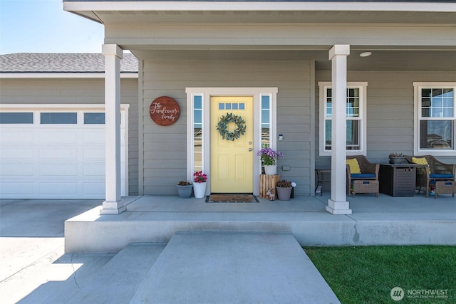 view of exterior entry featuring a porch, concrete driveway, and a garage