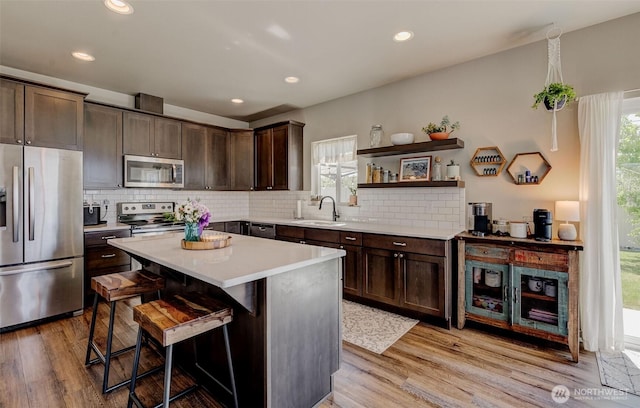 kitchen featuring a sink, appliances with stainless steel finishes, a wealth of natural light, and dark brown cabinets