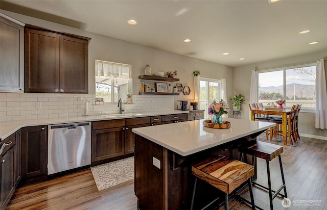 kitchen with a kitchen breakfast bar, dishwasher, a sink, light wood-style floors, and recessed lighting
