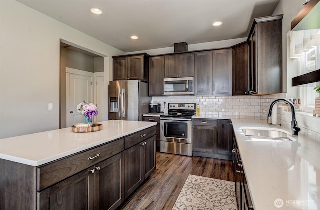 kitchen with dark brown cabinets, appliances with stainless steel finishes, a sink, and dark wood finished floors