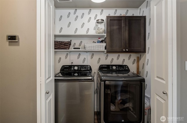 clothes washing area with separate washer and dryer and cabinet space