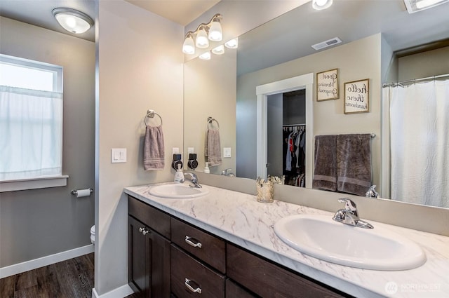full bathroom with a sink, baseboards, wood finished floors, and visible vents